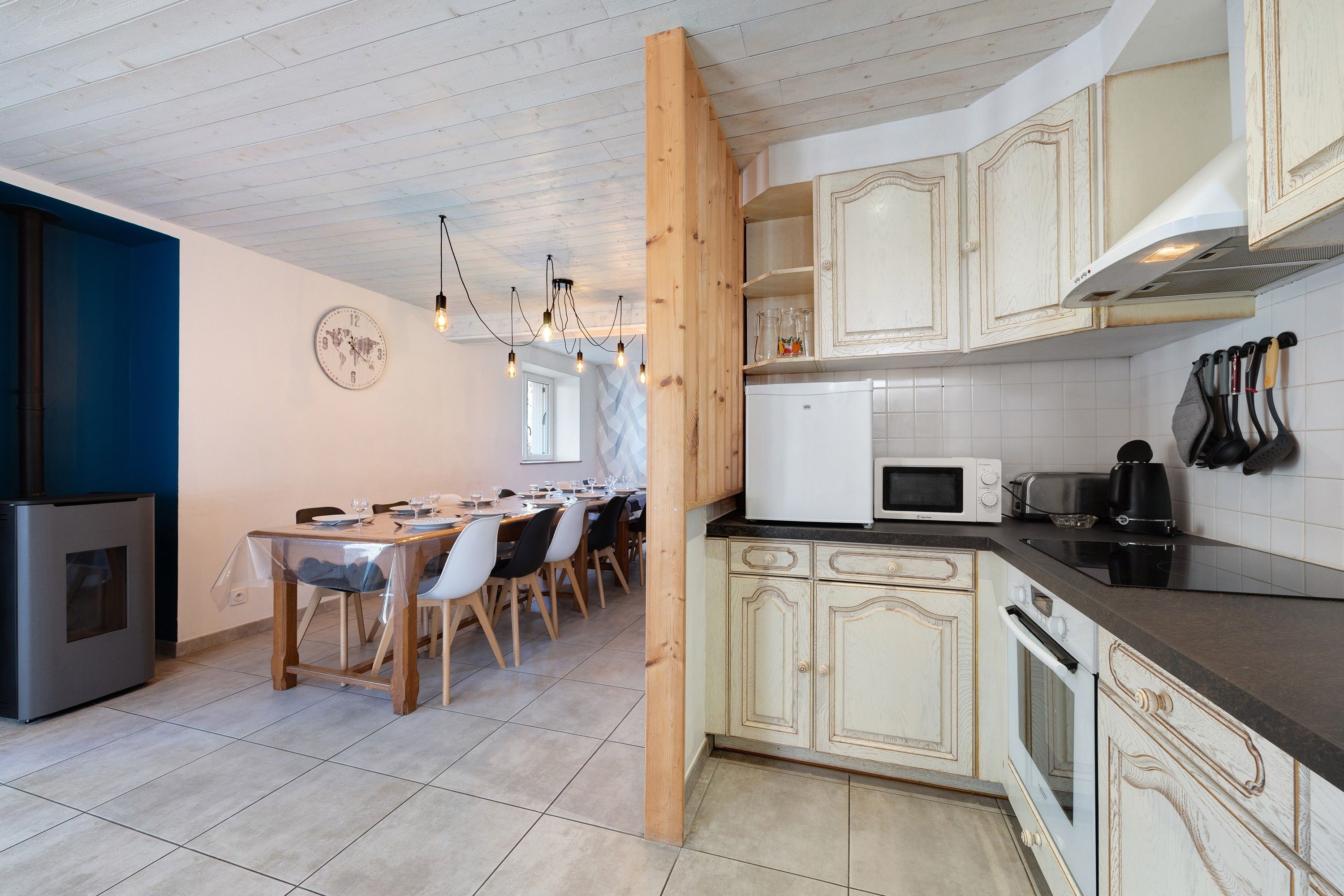 A modern kitchen with wooden cabinets, a dining area with a table set for four, and a built-in stove.