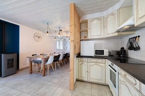 A modern kitchen with wooden cabinets, a dining area with a table set for four, and a built-in stove.