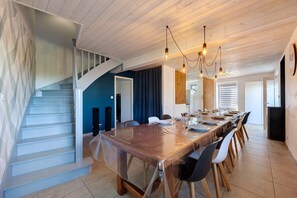Un área de comedor moderna con una mesa larga, sillas y una escalera.