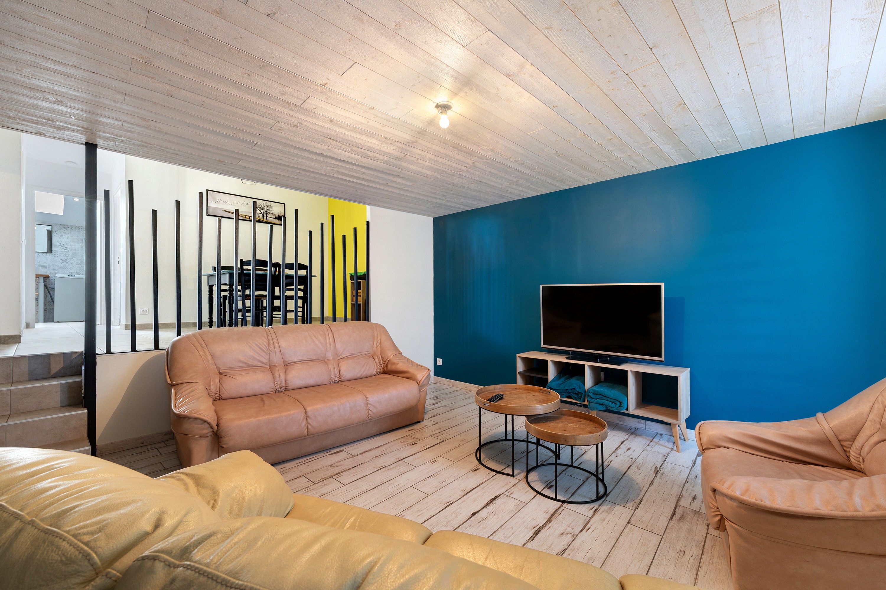 Una sala de estar moderna con un sofá, un televisor y una pared de acento azul.