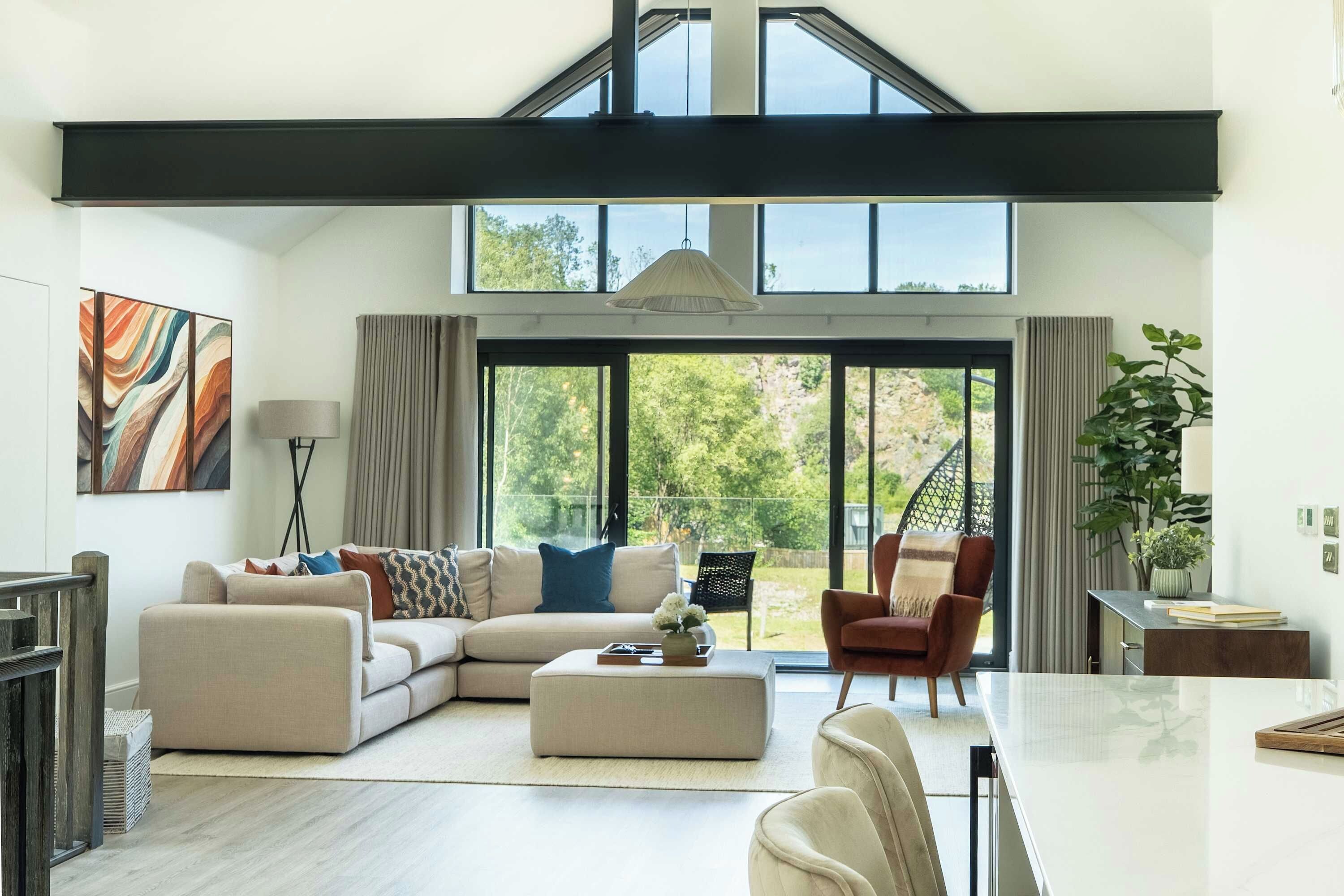 A spacious living room with a sectional sofa, a dining table, and a view of the outdoors through large windows.