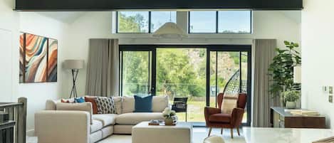 A spacious living room with a sectional sofa, a dining table, and a view of the outdoors through large windows.