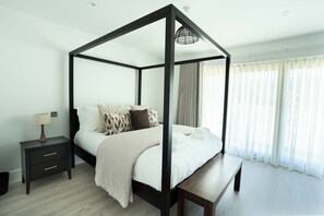 Una cama con dosel, un banco, una mesita de noche y una lámpara.