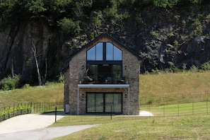 A two-story stone house with a large glass window and a balcony. - Luttrell House - 3 bed eco house (Somerset)