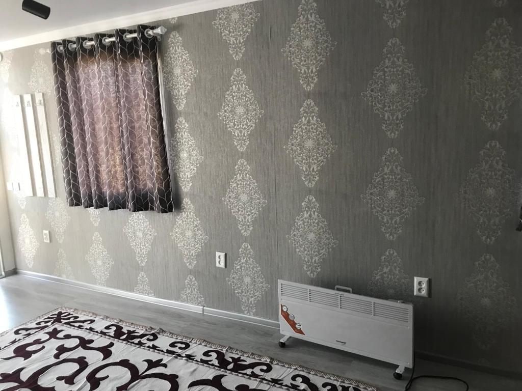 Una habitación con papel tapiz estampado, un radiador y un tapete con diseño.