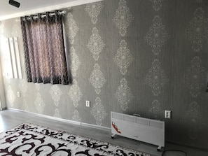 Una habitación con papel tapiz estampado, un radiador y un tapete con diseño.