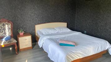 A single bed with a wooden frame and white bedding, a small bedside table with drawers, and a wall-mounted picture.