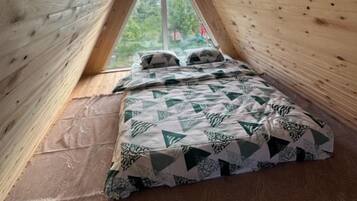 Une pièce triangulaire en bois, avec un lit et une fenêtre.