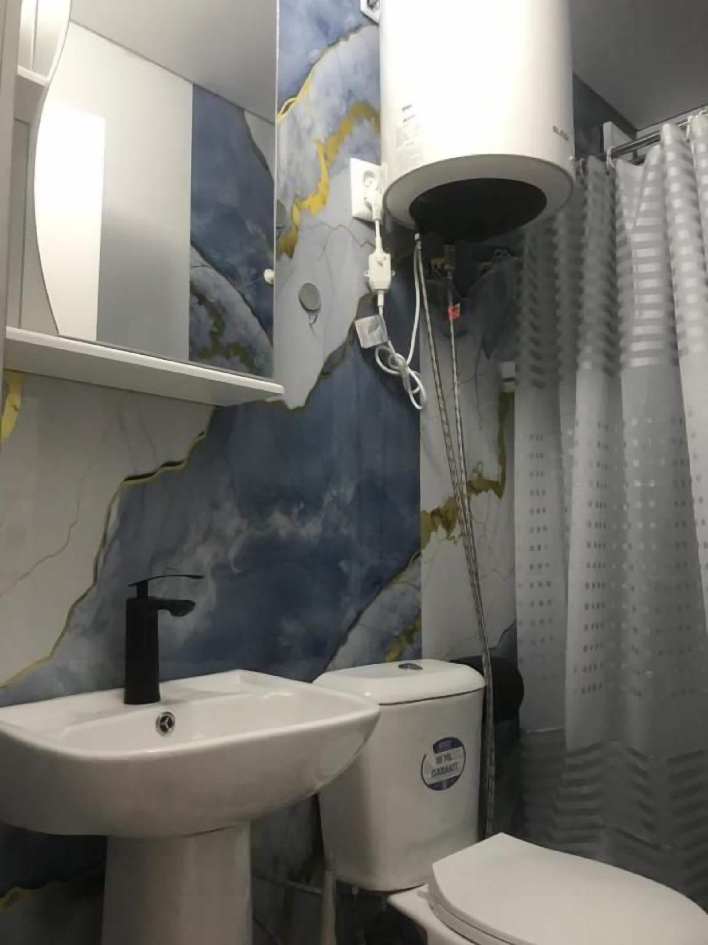 A bathroom with a white sink, a toilet, and a shower curtain.