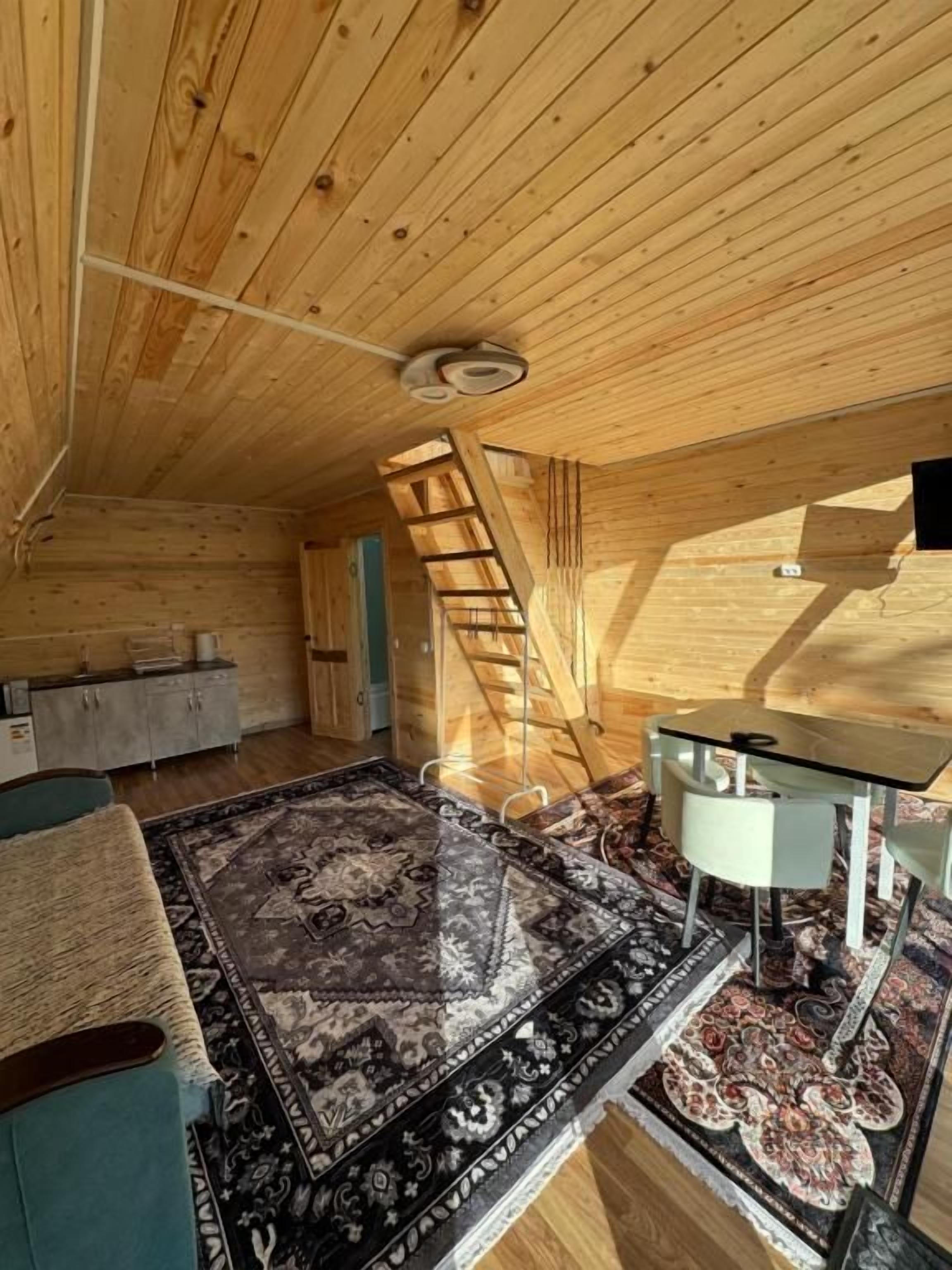 Un intérieur en bois avec un lit en mezzanine, une table à manger et un escalier.