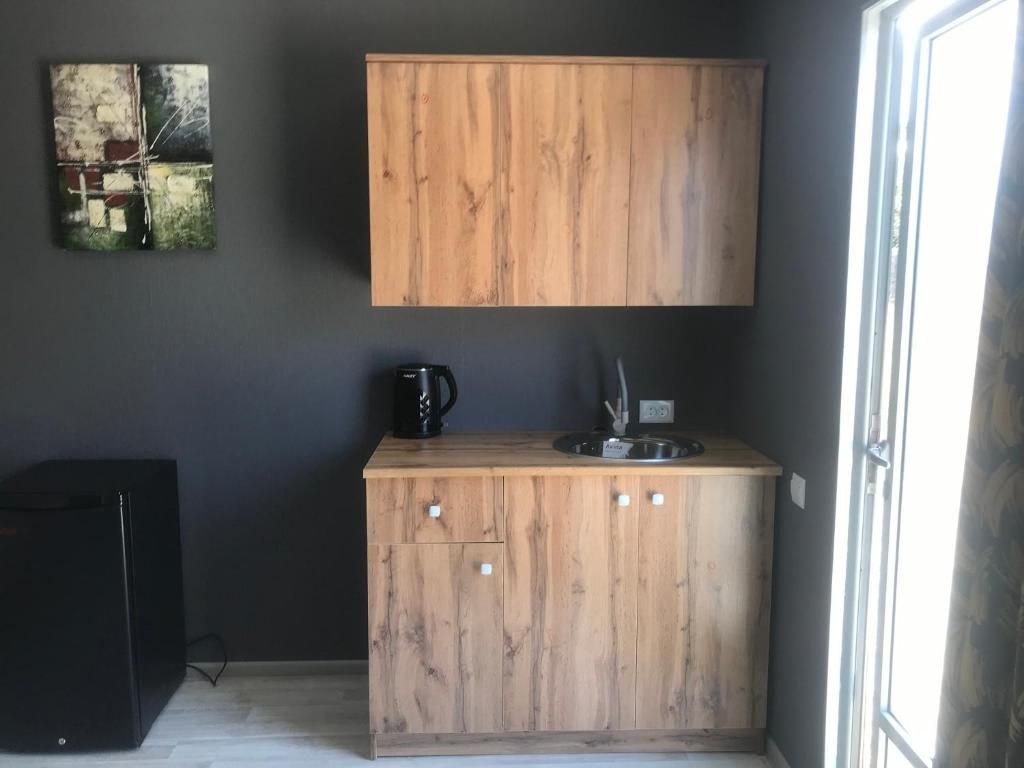 Une cuisine de taille réduite, avec un meuble en bois, une machine à café noire et un évier.