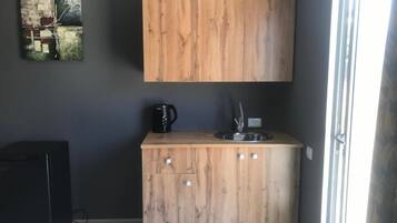 Une cuisine de taille réduite, avec un meuble en bois, une machine à café noire et un évier.