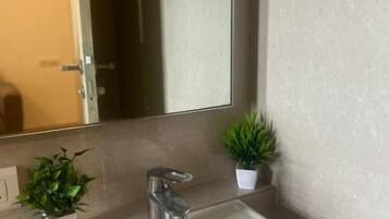 A bathroom with a white sink, a mirror, and two potted plants.