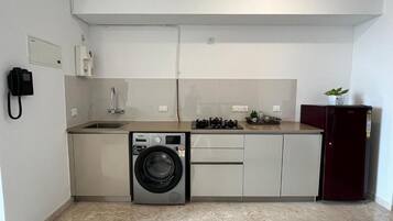 A compact kitchen with a washing machine, a sink, and a refrigerator.
