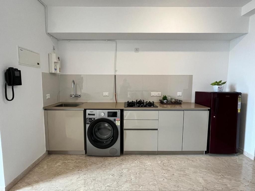 A compact kitchen with a washing machine, a sink, and a refrigerator.