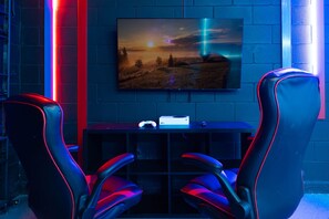 A gaming setup with two chairs, a TV, and a console on a table. - 3029 Magical Themed Home Dino Slide Pool Spa (Davenport)