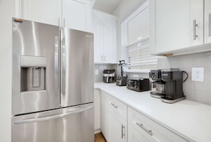 A modern kitchen with stainless steel appliances, including a refrigerator, a coffee maker, and a toaster. - 100 TV - Pool Spa Epic Game Room Villa for 14 (Kissimmee)