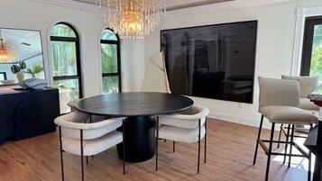 Een moderne eetruimte met een ronde tafel, vier stoelen en een kroonluchter.