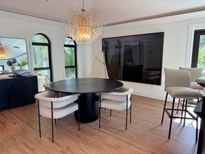 A modern dining area with a round table, four chairs, and a chandelier. - Kokomo Keys - Waterfront Heated Pool (Summerland Key)