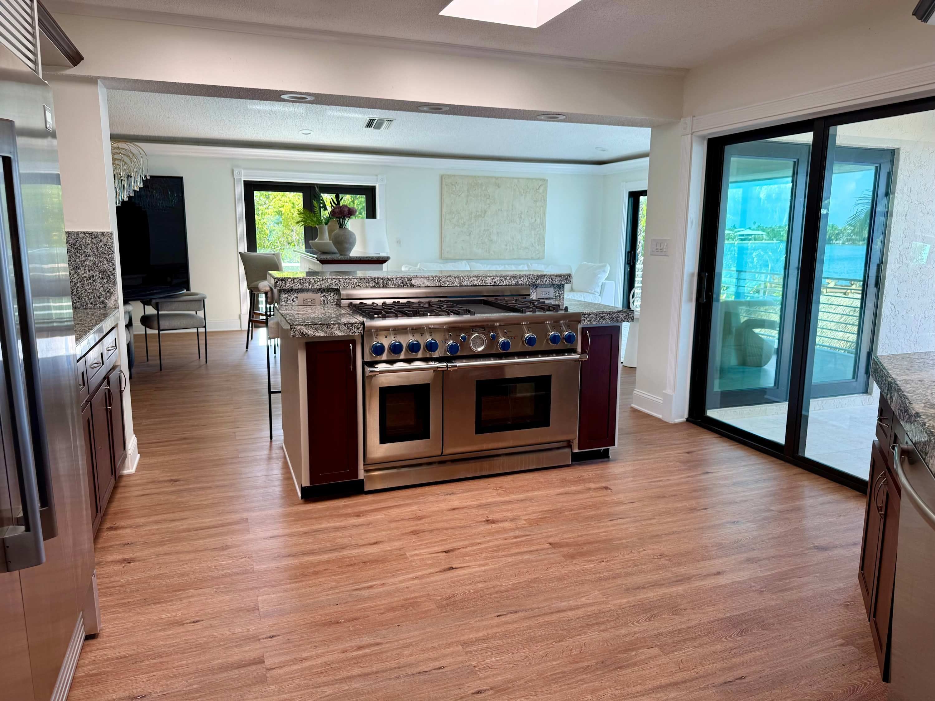 A modern kitchen with a built-in stove and oven, wooden flooring, and a sliding glass door leading to a balcony.