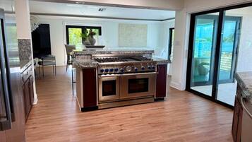 A modern kitchen with a built-in stove and oven, wooden flooring, and a sliding glass door leading to a balcony.