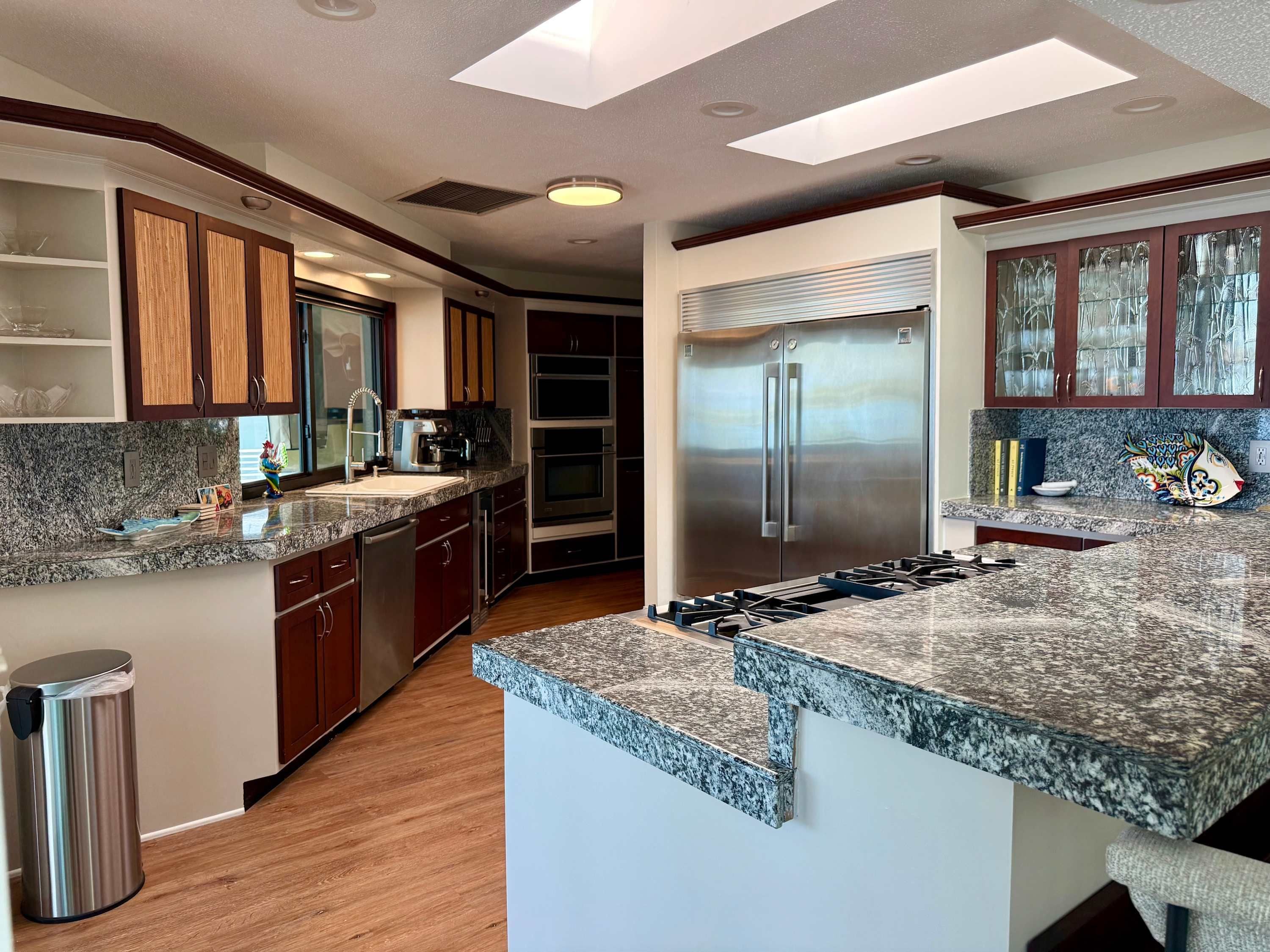 A modern kitchen with granite countertops, stainless steel appliances, and wooden cabinetry.