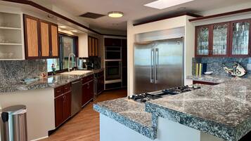 A modern kitchen with granite countertops, stainless steel appliances, and wooden cabinetry.