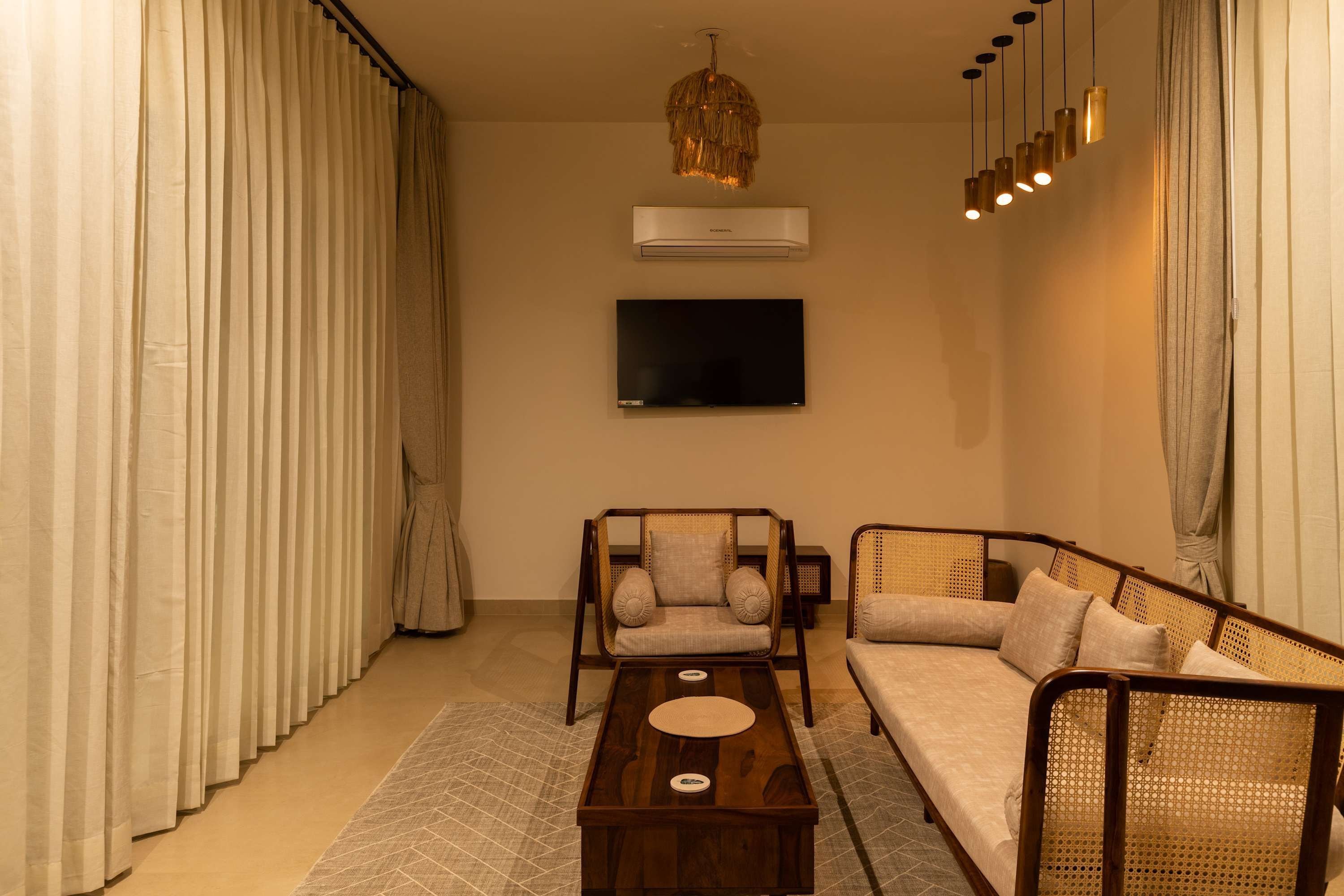 A living room with a sofa, a chair, a coffee table, a TV, and an air conditioner.