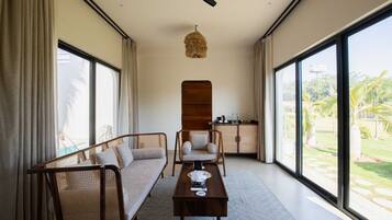 Una habitación amplia con sofá, sillón, mesa y ventilador de techo.