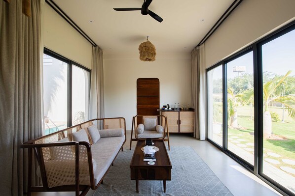 A spacious room with a sofa, a chair, a table, and a ceiling fan.