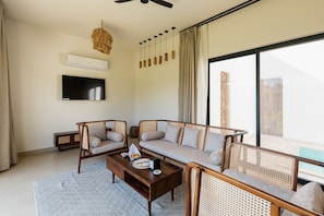 A modern living room with a sofa set, a coffee table, a flat-screen TV, and a ceiling fan.