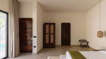 A bedroom with a bed, a wooden wardrobe, a door, and a window with curtains.