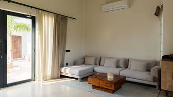 A modern living room with a sectional sofa, a wooden coffee table, and a large sliding glass door leading to an outdoor area.