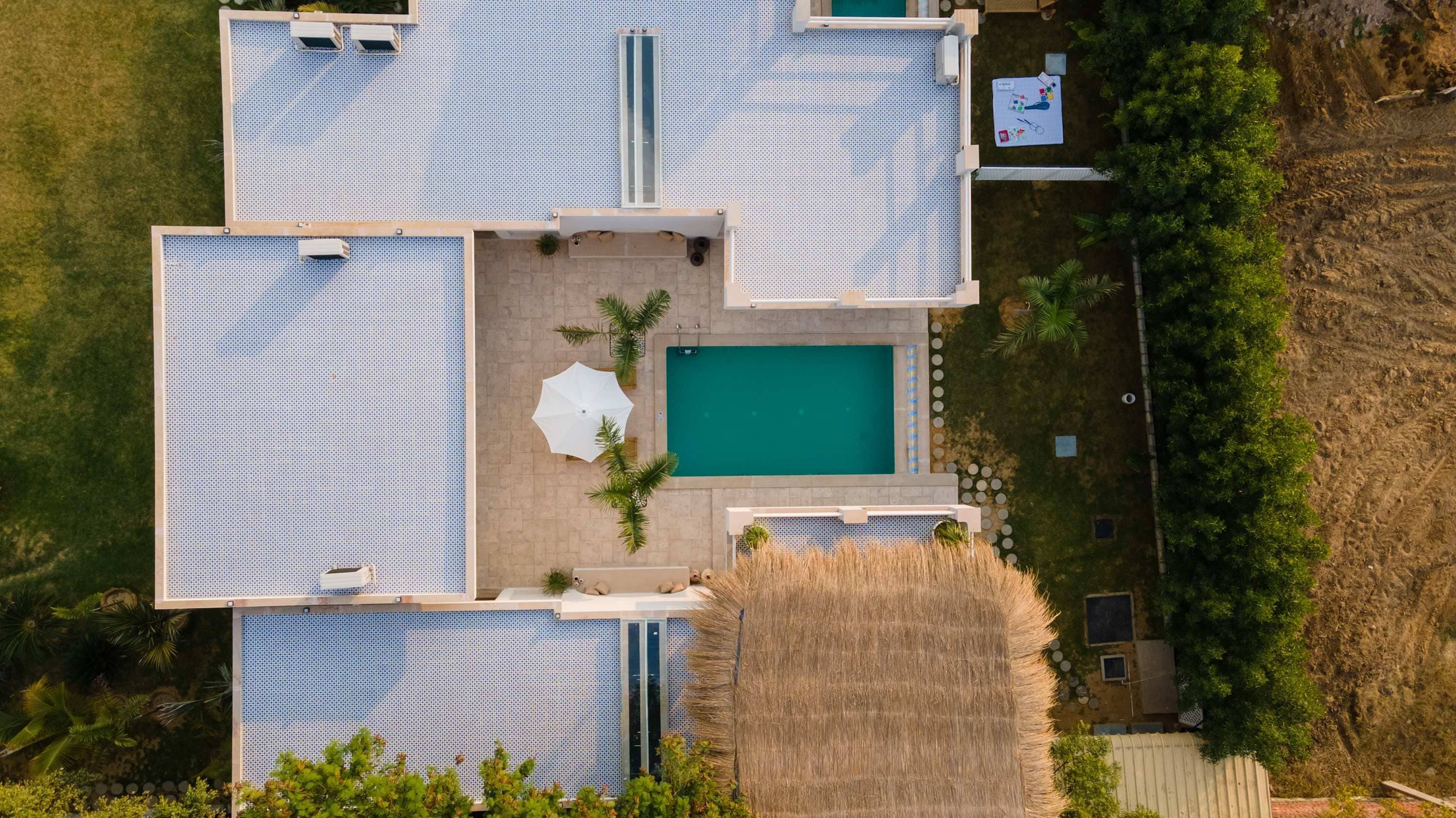A top-down view of a property with multiple swimming pools, a central pool, and surrounding outdoor seating areas.
