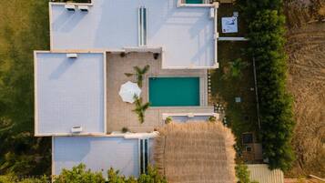 A top-down view of a property with multiple swimming pools, a central pool, and surrounding outdoor seating areas.