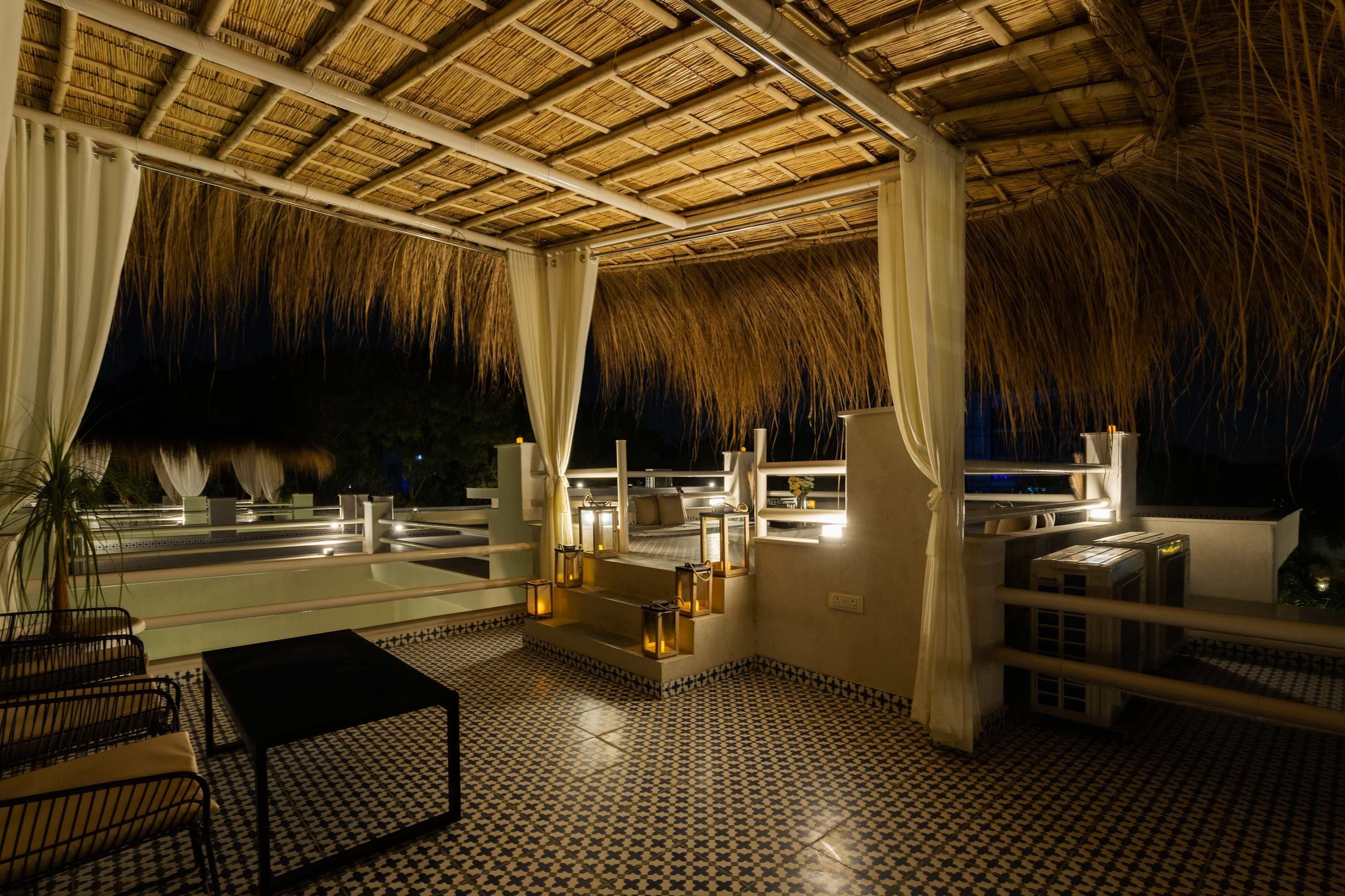 A covered outdoor area with a checkered floor, a pool, and a thatched roof.