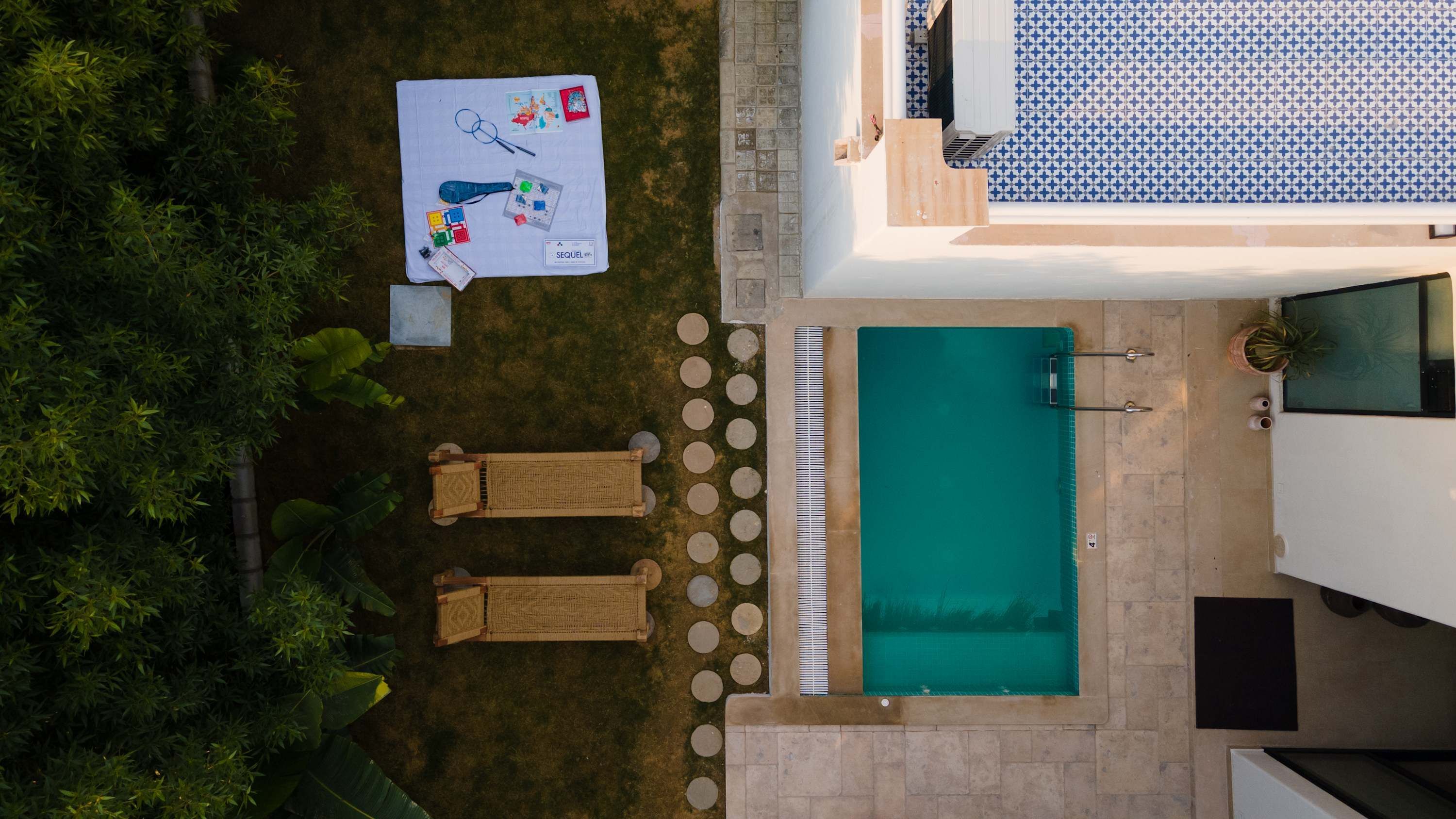 An aerial view of a property with a swimming pool, two lounge chairs, and a table with various items.