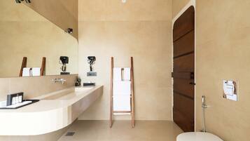 A modern bathroom with a large mirror, a sink, a toilet, and a shower.