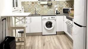 Een kleine keuken met een wasmachine, een magnetron en een koelkast.