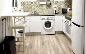 Uma cozinha compacta com máquina de lavar, micro-ondas e frigorífico.