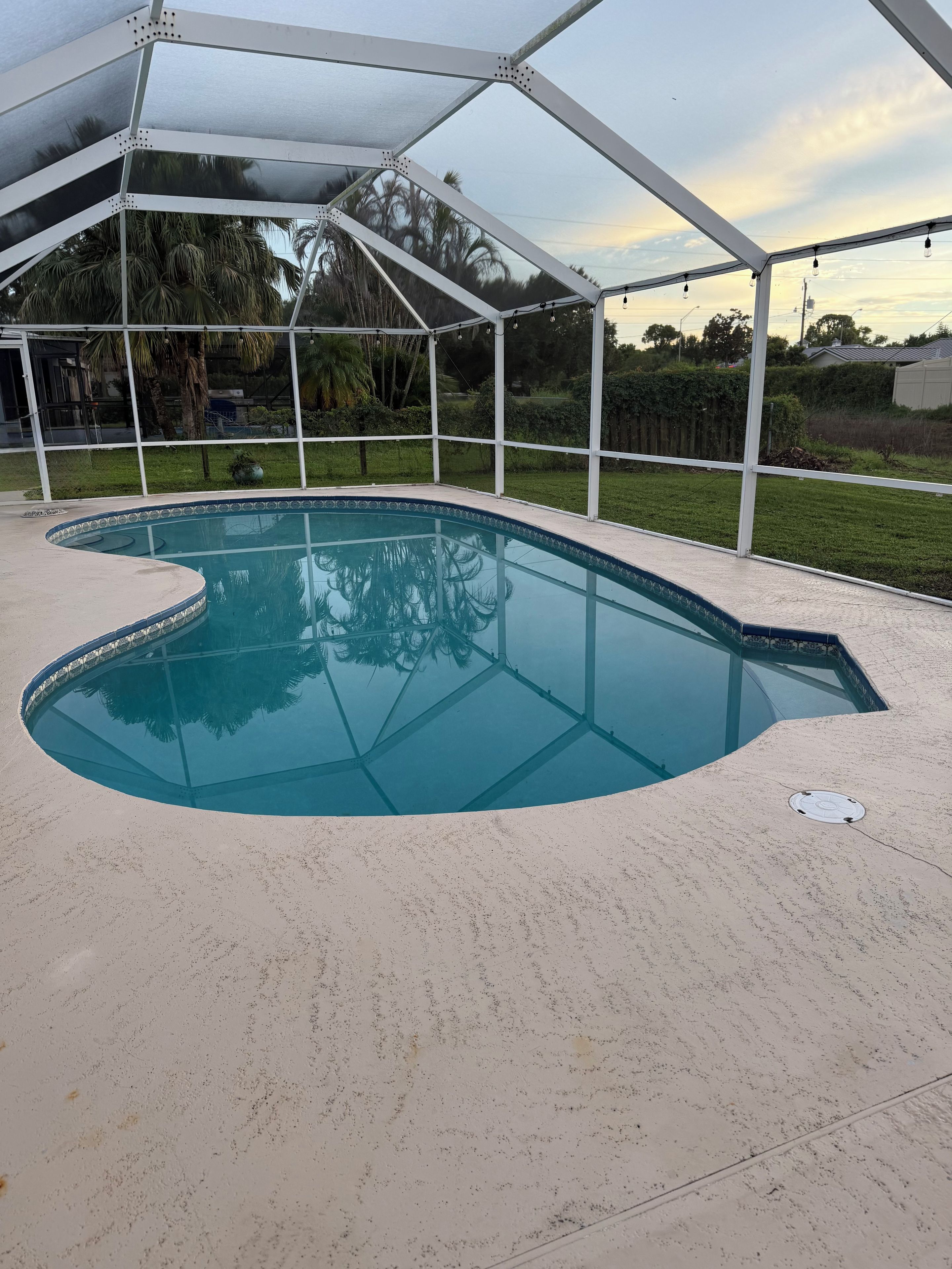 A swimming pool with a white deck and a covered area.