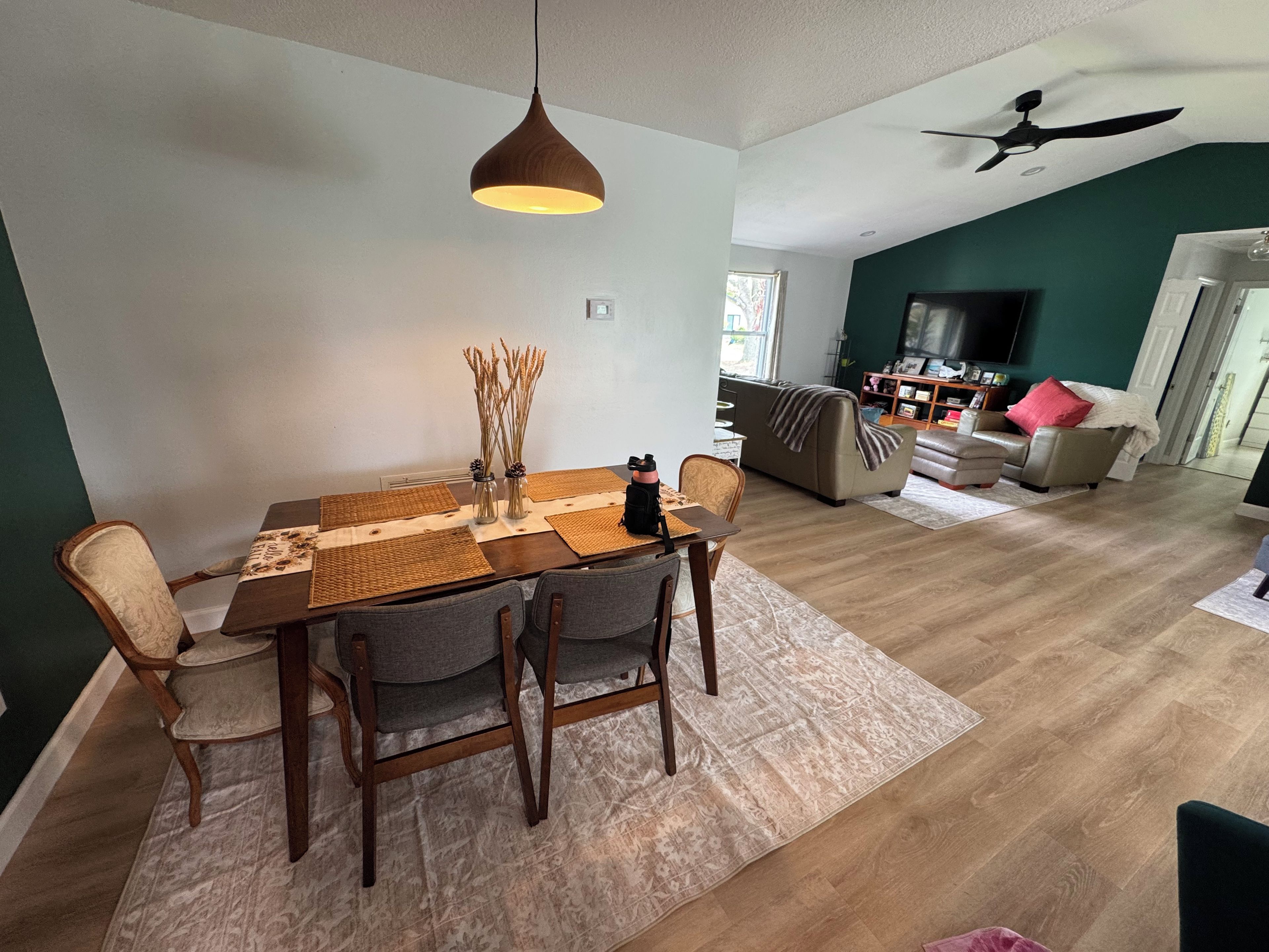 A dining area with a wooden table, chairs, and a hanging light fixture.