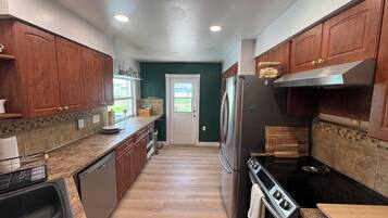 A modern kitchen with wooden cabinets, a stainless steel refrigerator, and a black stove.