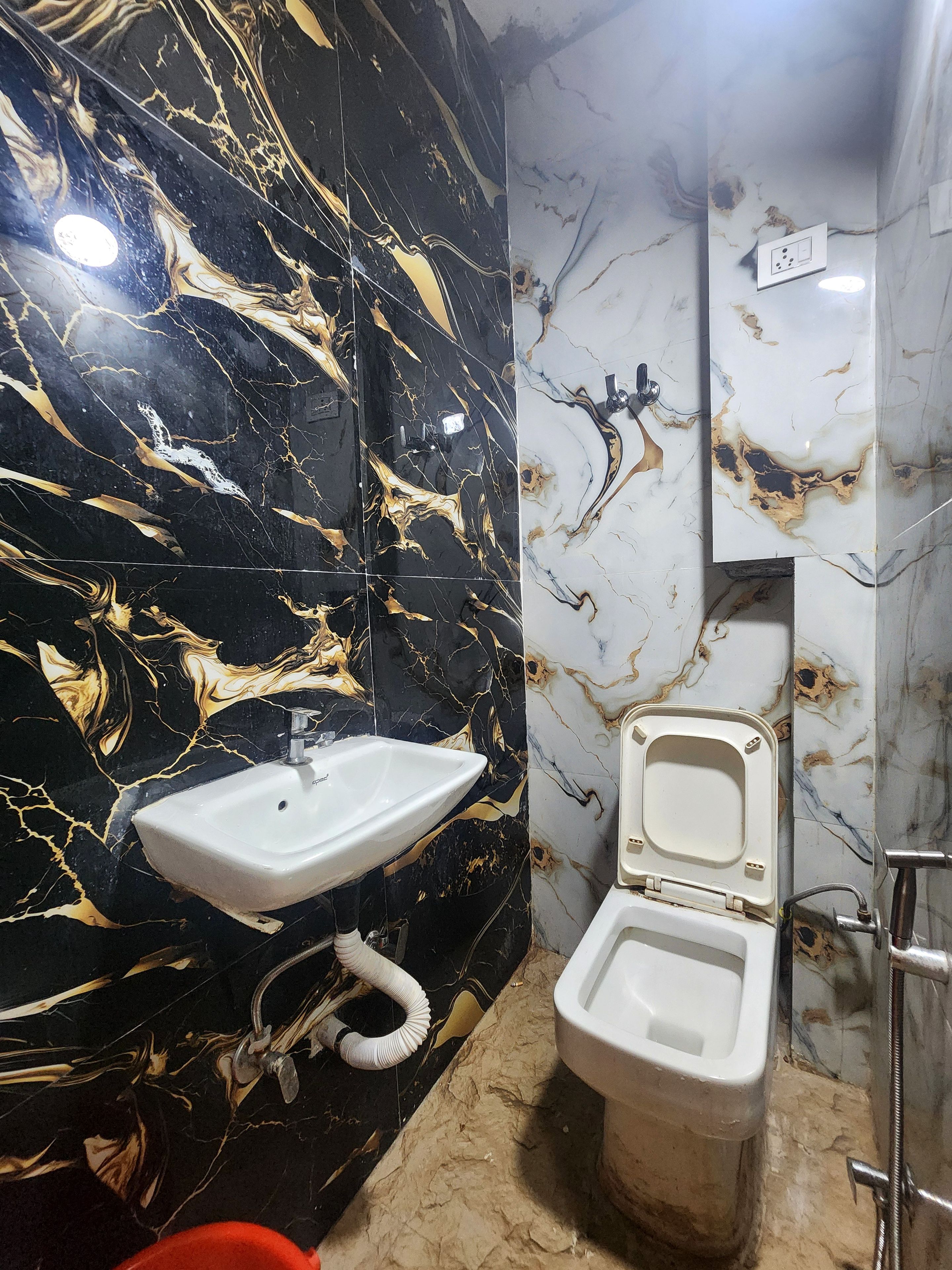 Een badkamer met een zwarte marmeren wand, een wit wastafel en een toilet.