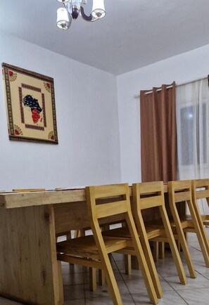 A dining area with a wooden table and chairs, a ceiling light fixture, and a framed picture on the wall. - SEED-Aeroport Nsimalen Yaounde (Yaounde)