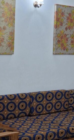 A room with a patterned sofa, a wall-mounted light fixture, and two floral wall decorations. - SEED-Aeroport Nsimalen Yaounde (Yaounde)