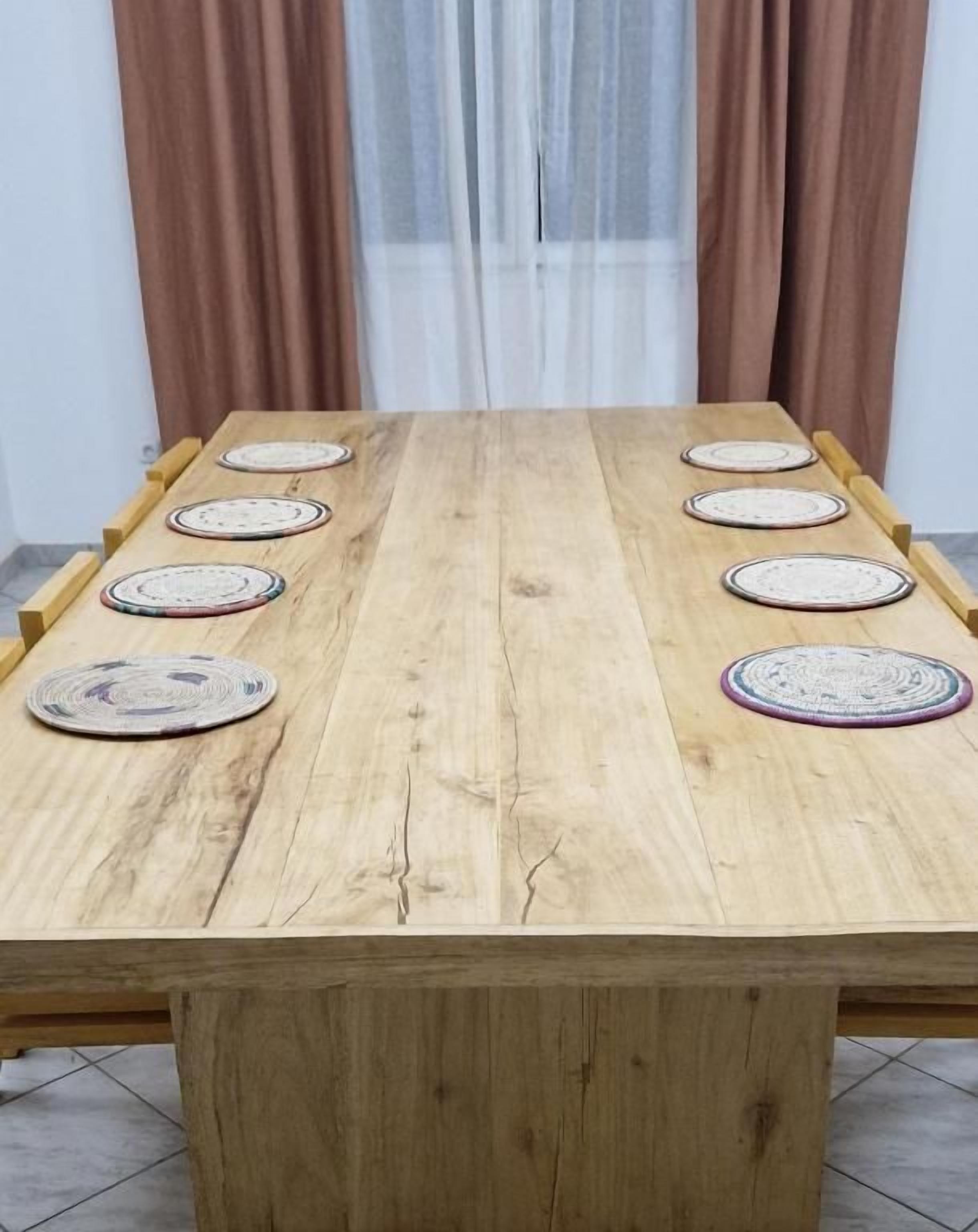 A wooden dining table with eight placemats and a central placemat.