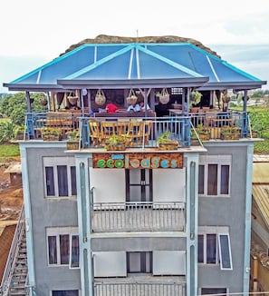 A multi-story building with a balcony area featuring potted plants and seating.