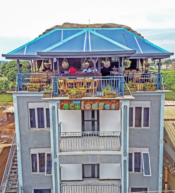 A multi-story building with a balcony area featuring potted plants and seating.