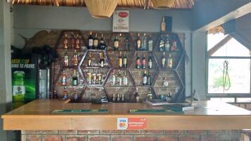 Een bar met een houten toonbank en een bakstenen muur. Er zijn verschillende kasten met flessen, en een bord dat aangeeft dat kaartbetalingen geaccepteerd worden.